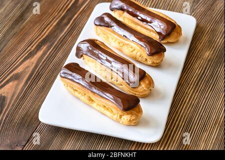 Eclairs with chocolate topping on serving plate Stock Photo