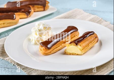 Eclairs with chocolate topping on serving plate Stock Photo