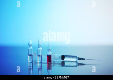 Syringe and ampoules on glowing blue reanimation light background Stock Photo