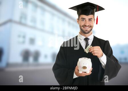 Student in graduation gown and cap on campus territory Stock Photo