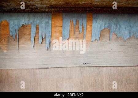 Old weathered flaky wood panel with rusty metal channel. Worn out veneer board with wood chips coming off. Rusty supporting metal bracket. Textured ab Stock Photo