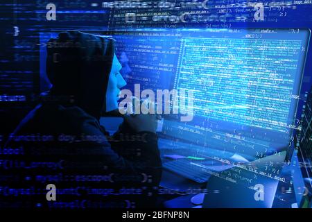 Hacker in mask using computer in darkness. Concept of cyber attack and security Stock Photo