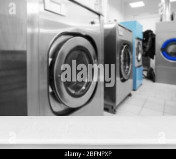 Table and washing machines at self-service laundry Stock Photo