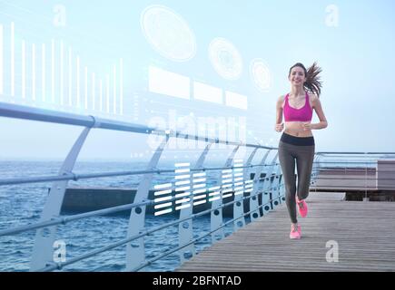 Heart rate monitor concept. Young woman running on pier Stock Photo