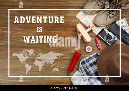 Text ADVENTURE IS WAITING and travel stuff on wooden background Stock Photo