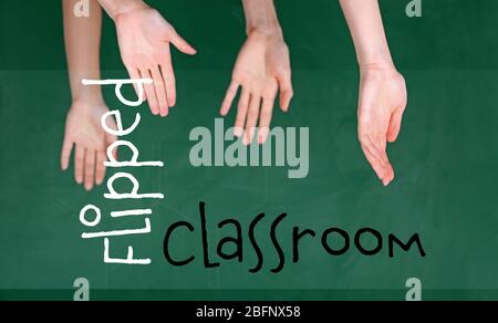 Flipped classroom concept. Inversed children's hands on blackboard background Stock Photo