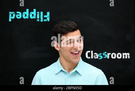 Flipped classroom concept. Young teacher on blackboard background Stock Photo