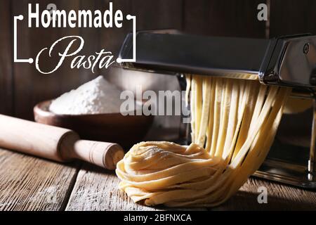 Raw homemade pasta and machine on wooden table Stock Photo