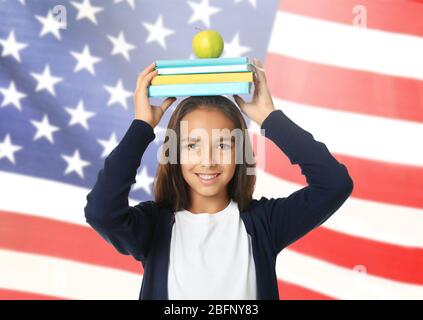 Little girl with apple and books on USA flag background Stock Photo