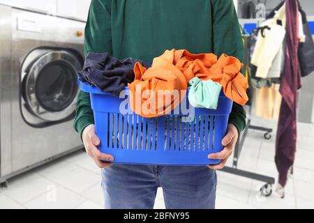 Dry cleaning concept. Man holding basket with clothes at laundry Stock Photo