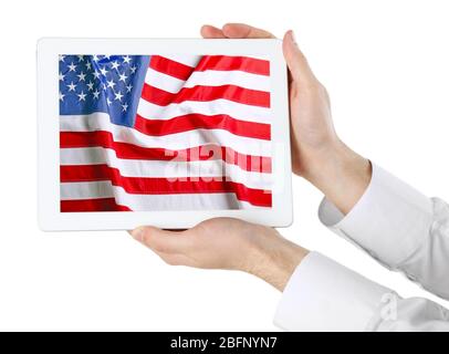 Young man holding tablet with American flag on screen against white background Stock Photo