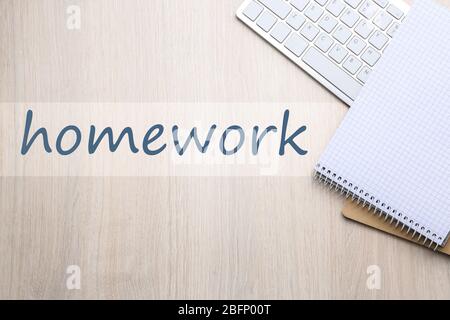 Flat lay composition with computer keyboard, notebooks and word HOMEWORK on wooden background Stock Photo