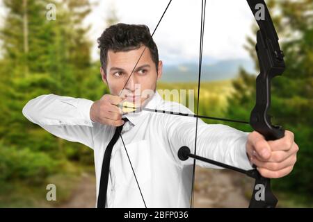Young businessman practicing archery and landscape on background Stock Photo