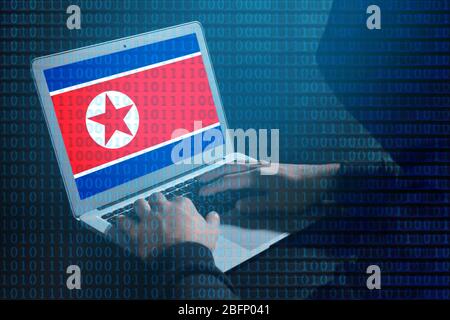 Hacker working with laptop at table. Flag of North Korea on screen. Threat of cyber attack against goverment Stock Photo