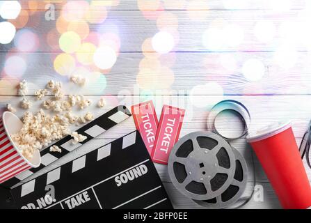 Flat lay composition with popcorn, filmstrips and blurred lights on wooden background. Cinema evening Stock Photo