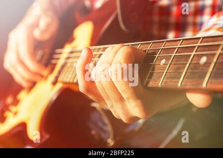 Young man playing on electric guitar on dark background with light effect Stock Photo