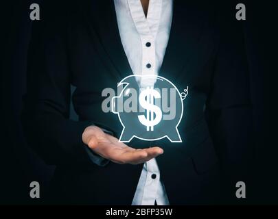 Female hand holding virtual piggy bank on dark background Stock Photo