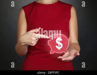 Female hands holding virtual piggy bank on gray background Stock Photo