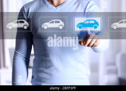 Young man touching icon of car on virtual screen Stock Photo