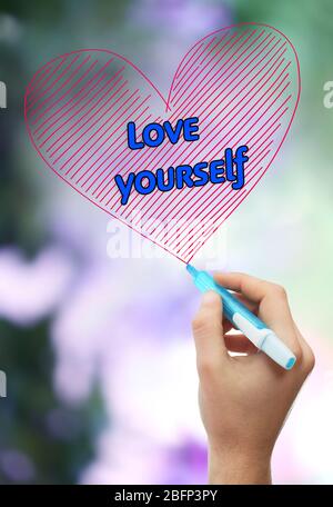 Male hand with marker writing Love yourself on natural background Stock Photo
