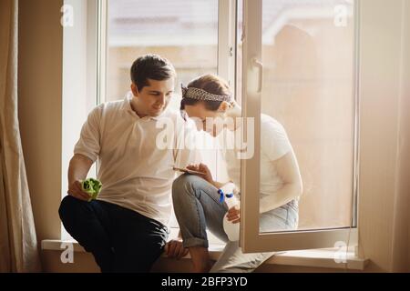 Young smiling couple is having rest after doing cleaning at home. Stock Photo