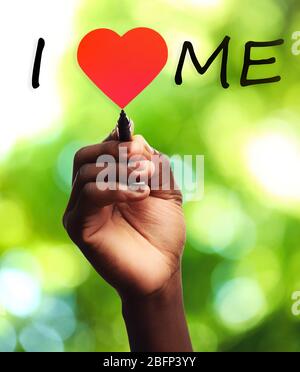 Love yourself concept. Male hand writing I Love Me on transparent whiteboard on natural background Stock Photo