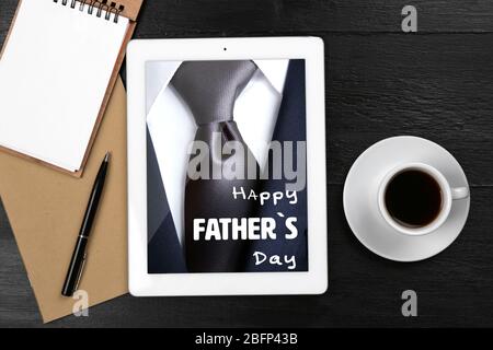 Happy father's day concept. Digital tablet with cup of coffee and notebook on wooden table, closeup Stock Photo