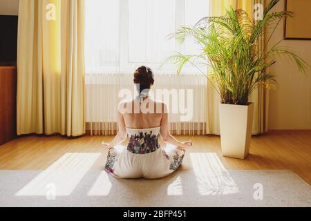 Back view of woman meditating on floor at home. Stock Photo