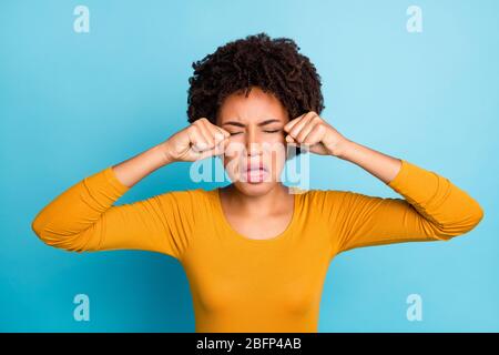 Portrait of disappointed sad afro american girl have argument suffer quarrel start cry touch fists eyes wear stylish trendy jumper isolated over blue Stock Photo
