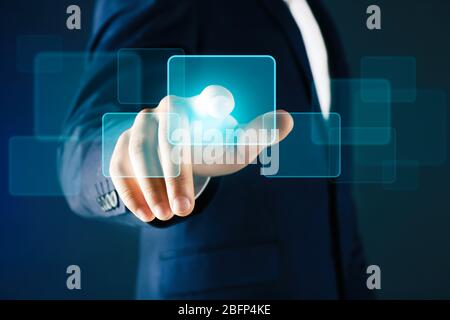 Businessman in suit pushing a button on virtual screen Stock Photo