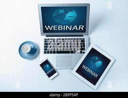 Different modern devices with cup of coffee on light table. Webinar concept Stock Photo