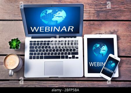 Different modern devices with cup of coffee on wooden table. Webinar concept Stock Photo