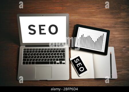 SEO technology concept. Laptop, tablet and phone on wooden background. Stock Photo