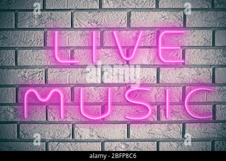 Neon text live music on brick wall background. Stock Photo