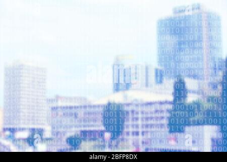 Binary code on blurred cityscape background. Stock Photo