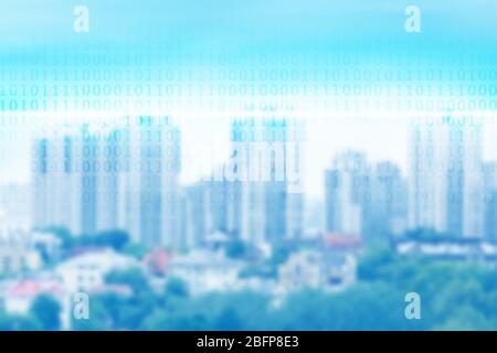 Binary code on blurred cityscape background. Stock Photo