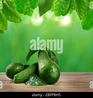 Fresh avocados on wooden table. Blurred green background. Stock Photo