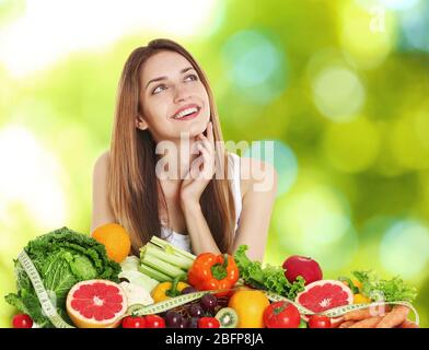 Beautiful young woman with healthy food on blurred green background. Diet concept. Stock Photo