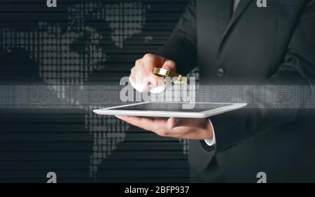 Businessman holding magnifying glass and tablet. Binary code and world map on background. Technology concept. Stock Photo