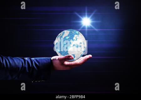 Businessman holding digital earth on dark background. Technology concept. Stock Photo