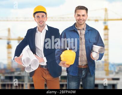Professional engineers with blueprint on blurred city background Stock Photo
