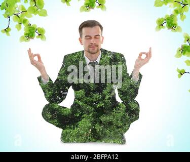 Double exposure of tree leaves and businessman sitting in lotus pose with blue background. Yoga concept. Stock Photo