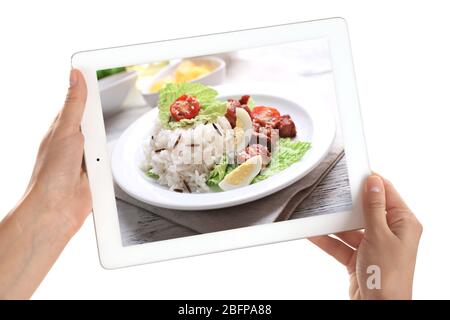 Female hands holding tablet on white background. Photo of food on tablet screen. Stock Photo
