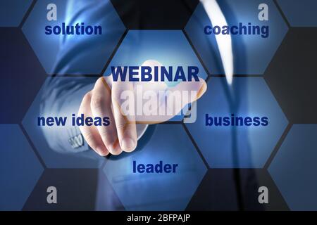 Businessman pushing WEBINAR button on virtual screen. Business coaching and modern technology concept. Stock Photo