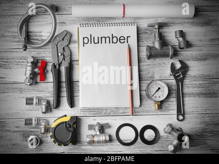 Plumbing concept. Plumber tools with notebook on wooden textured background Stock Photo