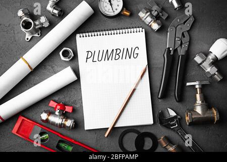 Plumbing concept. Notebook and plumber tools with blueprints on concrete structure background Stock Photo