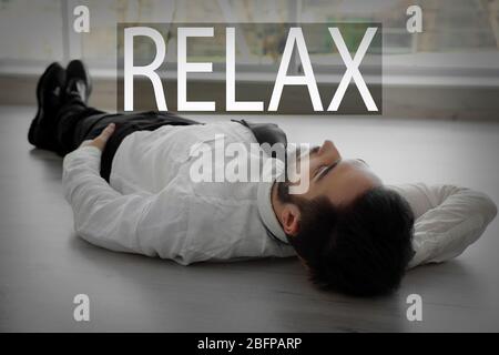 Word RELAX and young businessman lying on the floor. Stock Photo