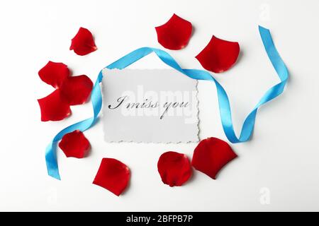 Rose petals, ribbon and card on white background Stock Photo