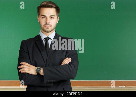 Young teacher on chalkboard background. School and education concept. Stock Photo
