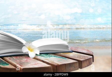 Reading during summer vacation. Book and flower on landscape background Stock Photo